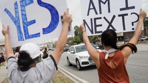 Demonstrators hold signs while participating at a rally against anti-Asian hate on March 27, 2021, in Chamblee, Ga.