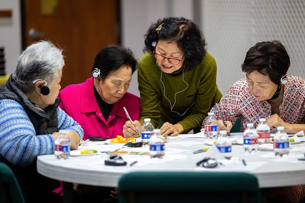 Four Korean people gathered around a table.