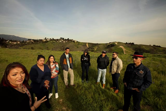 Gabrielino Shoshone Tribe members Jaime Rocha, left, her mother Eileen Rocha, Jaime’s sister Cheyenne Rocha, along with Tecpatl Kuauhtzin, Minnie Ferguson, Victorino Torres-Nova, Trinidad Ruiz and Marcos Aguilar, all from the Anahuacalmecac International University Preparatory of North America, stand on a vacant site where an extension of their school will be built in Monterey Hills.