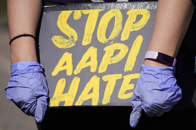 Woman holds a sign and attends a rally to support stop AAPI (Asian Americans and Pacific Islanders) hate at the Logan Square Monument in Chicago